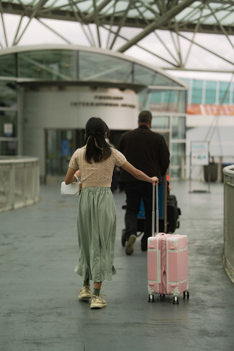 woman in brown t shirt pushing her pink luggage and man in black long sleeves pushing trolley — Après-midis musée avec audioguides en streaming, pas en mise en mémoire.