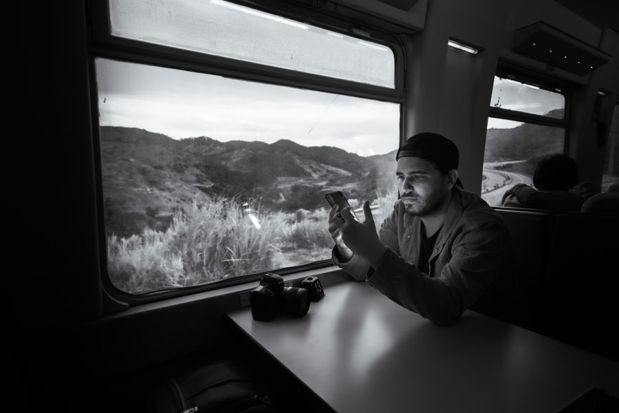 Man using a smartphone on a train journey through scenic landscape. — Routes côtières au-delà de Tunisia : la carte suit votre rythme où que vous alliez.