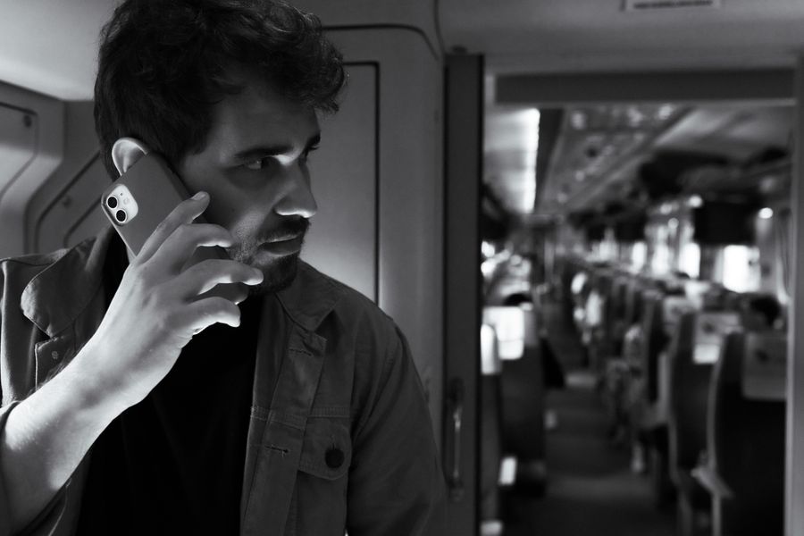 Black and white photo of a man using a smartphone while traveling on a modern train. — How Much Speed Do You Need?: one question, answered well, instead of ten open tabs.