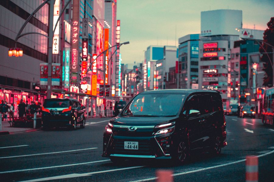 black toyota noah driving down the street in tokyo — Le road trip en Rwanda : arrêts carburant planifiés, playlist téléchargée, carte hors ligne.