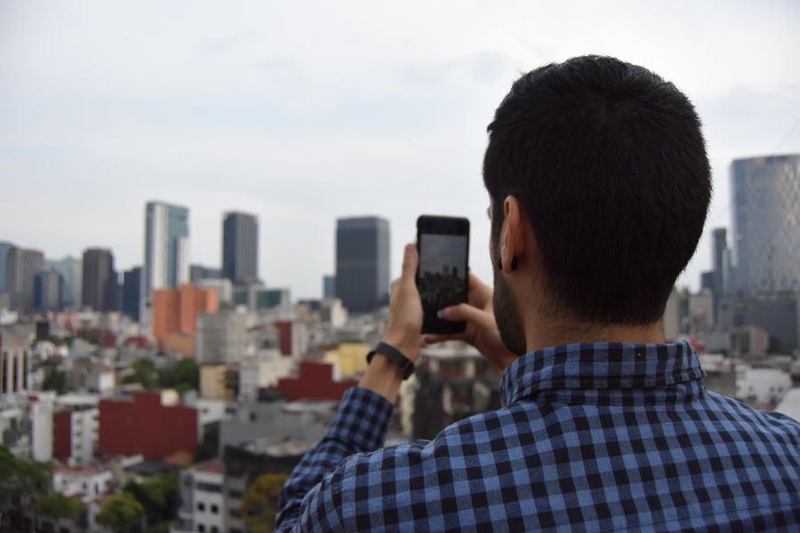 Man photographing urban cityscape with smartphone against skyline. — Le trajet en Morocco : podcasts, messages et cartes, aucune zone blanche.