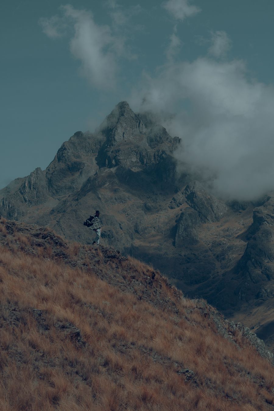 man with a backpack standing on a mountain slope — De gare en gare à Burkina Faso : tout passe par le téléphone.