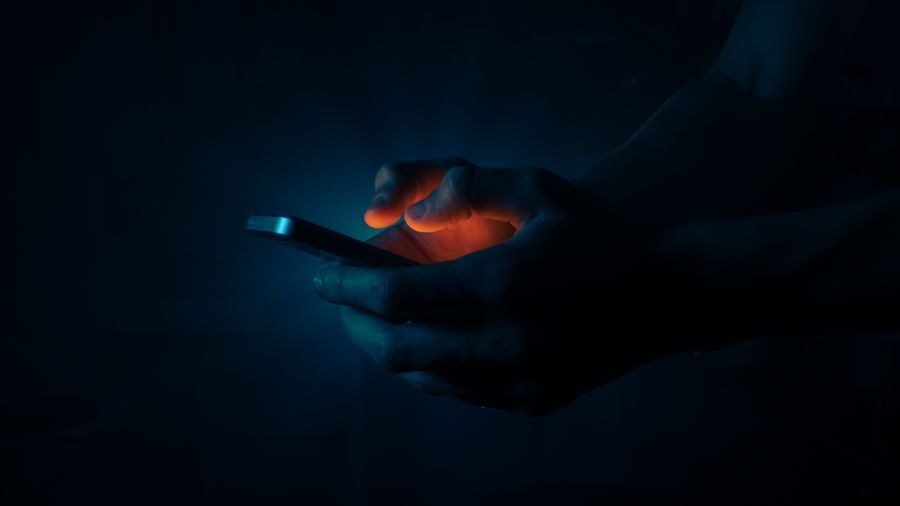 man holding a mobile phone in the dark