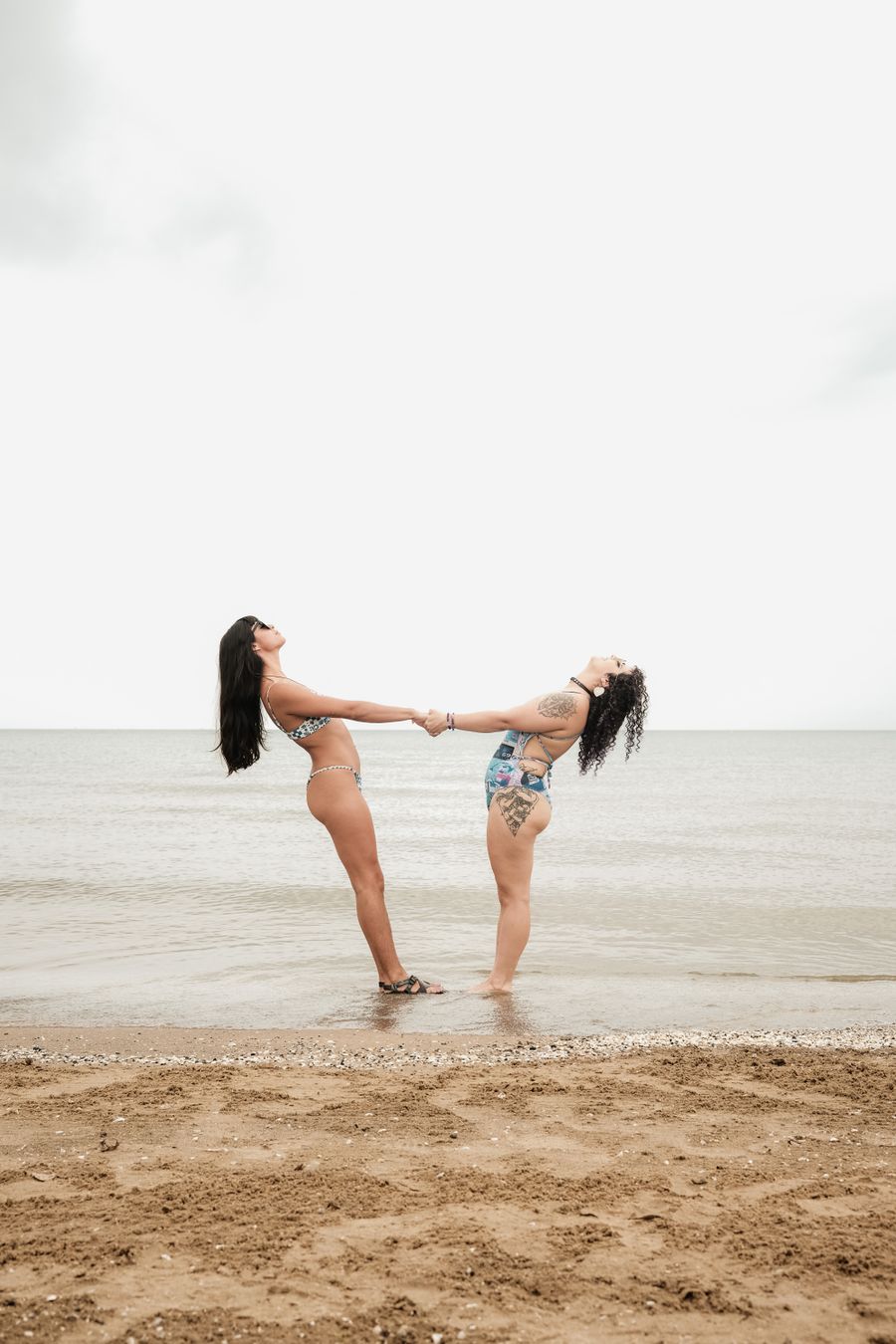 two women standing on the beach holding hands — Dialing Helper: the fastest way to turn a vague travel question into a next step.