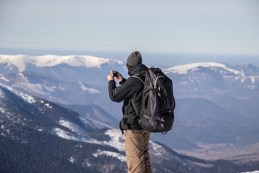 A person capturing the stunning view of snowy mountains with a smartphone. — Docs: Les files d'enregistrement avancent plus vite quand vos documents sont sur le téléphone.