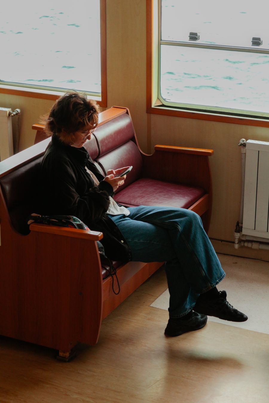 A woman sitting comfortably on a ferry, enjoying a peaceful journey. — L'agent garde votre numéro WhatsApp actif pendant que les données passent par l'eSIM.