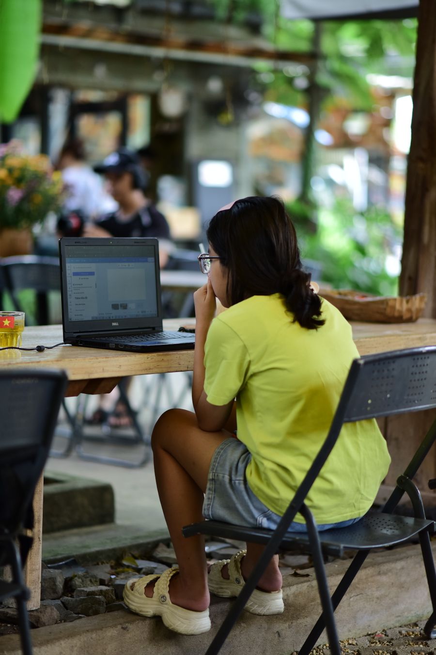 woman working on laptop in outdoor cafe setting — Street level: navigation, rideshares and reviews, all instant.