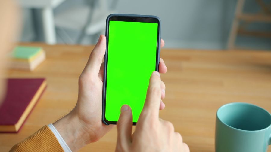 person using smartphone with green screen at desk — Campagne en DR Congo : la ferme trouvée, le code du portail dans les messages.