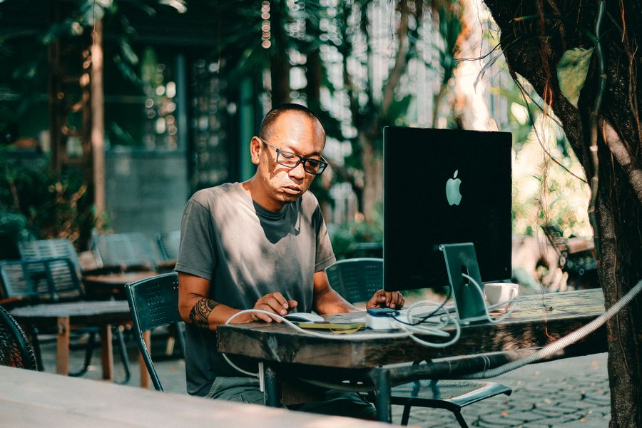 man working on computer at outdoor cafe — Le trajet en DR Congo : podcasts, messages et cartes, aucune zone blanche.