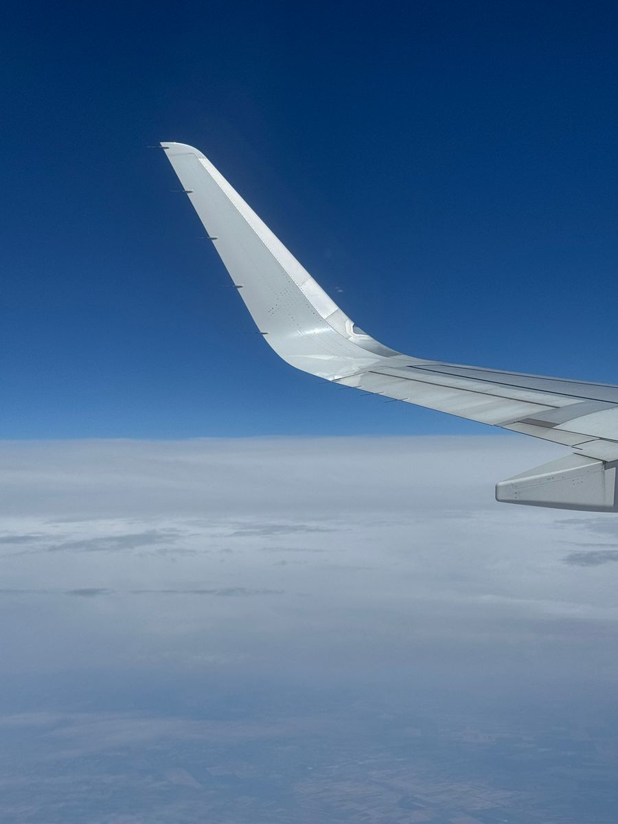 airplane wing above the clouds on a clear day — Docs: De quai en quai : billets, horaires et taxis dans une main.