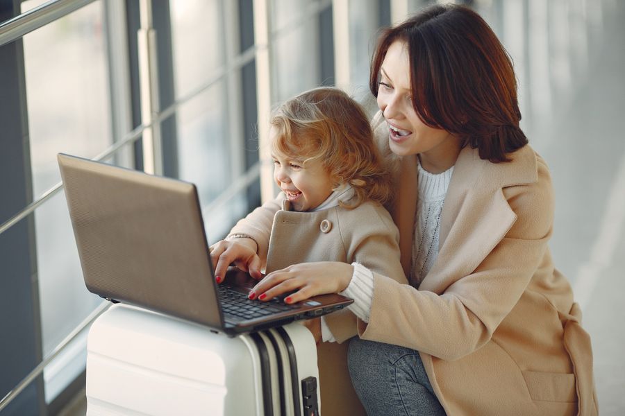 delighted mother with daughter typing on laptop in airport — Marchés de Belgium : marchandez convertisseur ouvert, payez d'un toucher.
