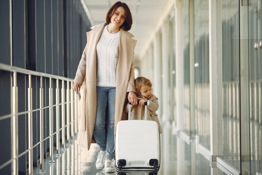 positive mother and daughter with suitcase in airport corridor — Pays du vin près de Haiti : la visite réservée, le chauffeur appelé, les photos sauvegardées.