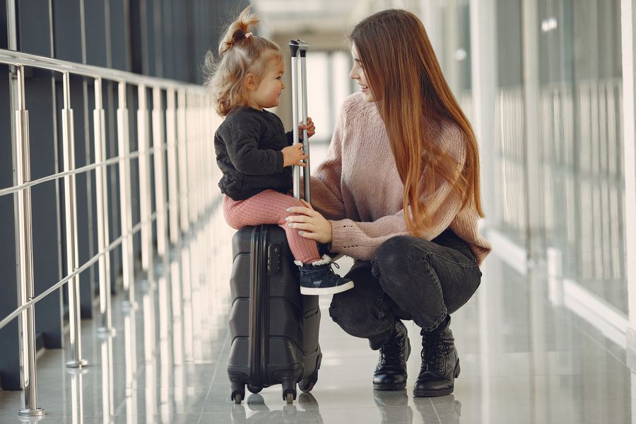 smiling mother with daughter and suitcase in airport — Soirées à Morocco : dîners, trajets et avis, tout instantané.