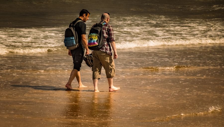 men with backpacks walking on the beach — Street-food stalls and mobile pay: dinner ordered without a word of the language.