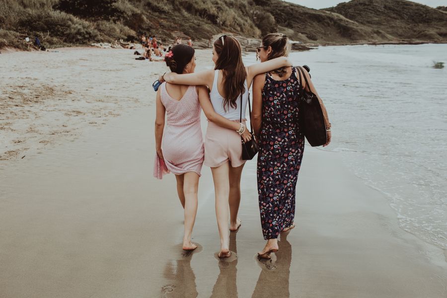 cheerful girlfriends walking together along sandy beach — Données basses en plein voyage ? L'agent vous conduit à la recharge en un toucher.