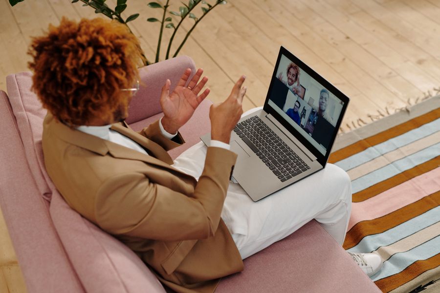 man sitting on sofa talking on webcam on laptop — Le derby de Tunisia : billets scannés, ralentis en streaming, retour réservé.