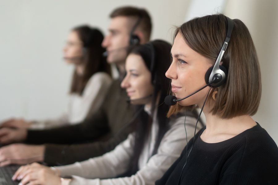 operators with headphones with microphone working on netbook in room — Developers: Coworking à l'étranger : ordinateur partagé, appels nets, délais tenus.