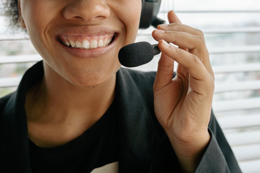 close up photo of a smiling woman holding microphone — Le hall des arrivées de Morocco : en ligne avant le tapis à bagages, à chaque fois.