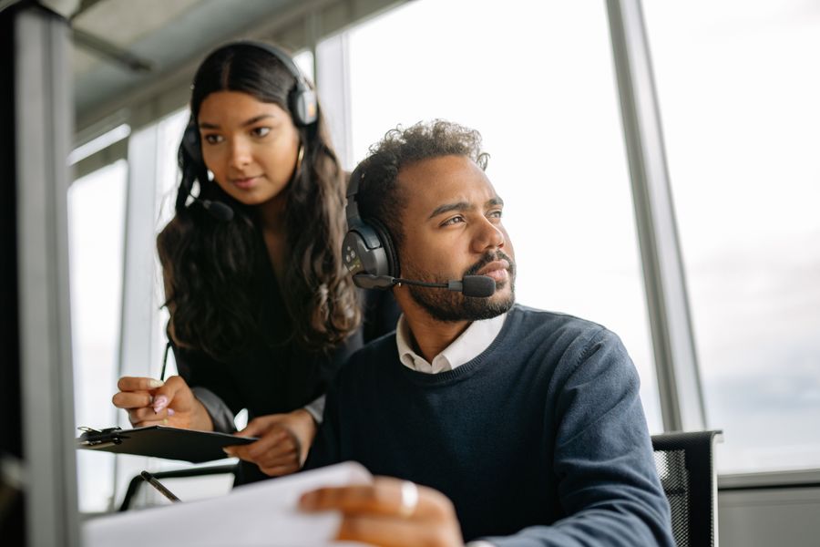 man and woman wearing headphones while working in the office — Le Tele Agent joint le bon format de numéro pour votre destination.